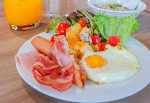 a plate of breakfast food with eggs bacon and vegetables at Riva Vibe Hotel Bangkok by PCL in Bangkok