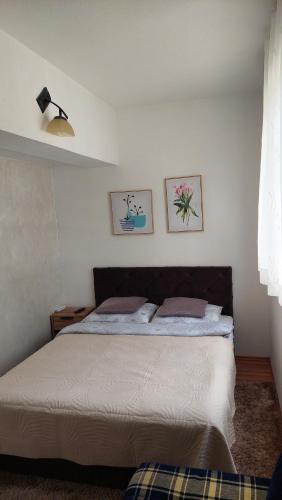 a bed in a bedroom with two pictures on the wall at Apartman Vlašićki san in Vlasic