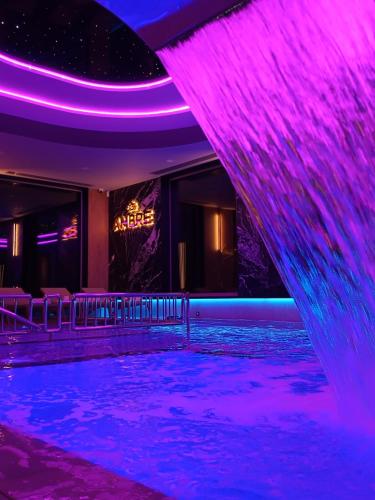 Un escenario con iluminación violeta y un estanque de agua. en Rezydencja AMBRE, en Łeba