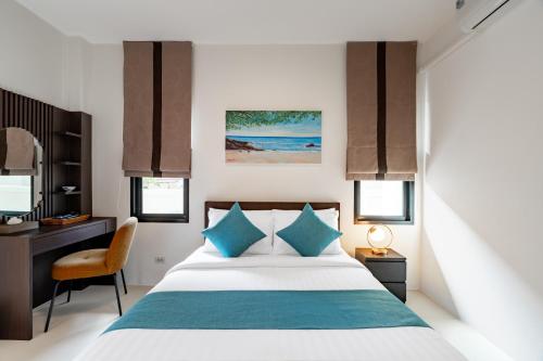 a bedroom with a bed with blue pillows and a desk at Baan Piengfah Holiday Home Ao Nang in Ao Nang Beach