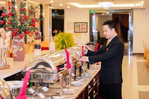 ヴィンにあるMuong Thanh Thanh Nien Vinhの男がビュッフェ形式で料理を作っている