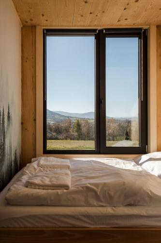 a bed in a room with two large windows at Hvile, gmina Brenna - BESKIDY in Górki Wielkie
