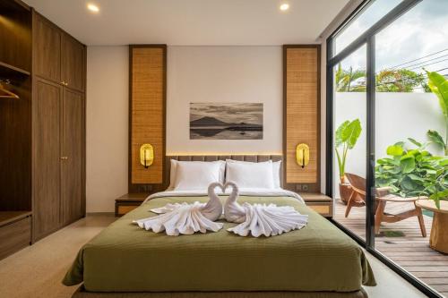 dos cisnes están sentados en una cama en un dormitorio en Villa Mewangi by SooBali Private Pool in Sanur, en Sanur