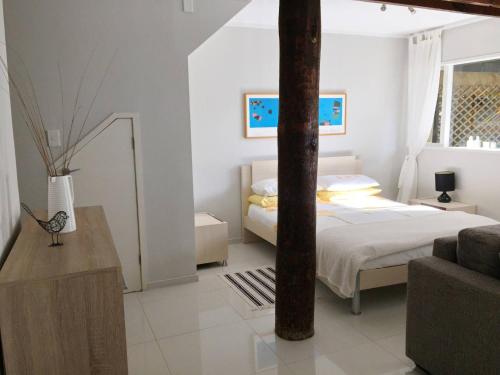 Un dormitorio blanco con una cama y un sofá. en Relax in Titirangi Cozy Studio Apartment, en Parau