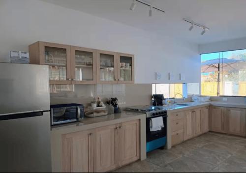 Casa Siena Vichayito a poco metros del mar في لوس أورغانوس: مطبخ بخزائن خشبية وثلاجة بيضاء