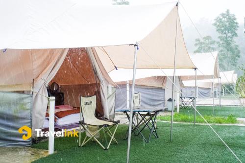 a tent with chairs and a bed in the rain at Sun CampGround in Kejajar