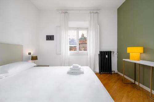 a white bed in a room with a window at Casa Lusso con 3 Camere con Affaccio Esclusivo su San Petronio in Bologna