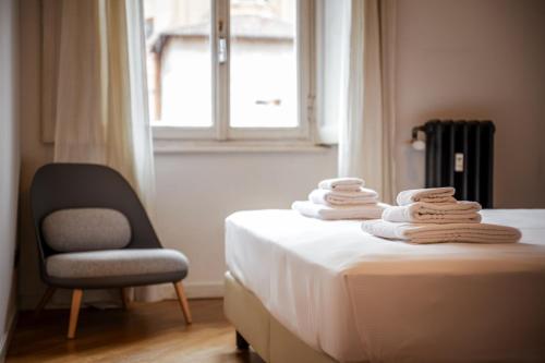 a pile of towels on a bed with a chair at Casa Lusso con 3 Camere con Affaccio Esclusivo su San Petronio in Bologna