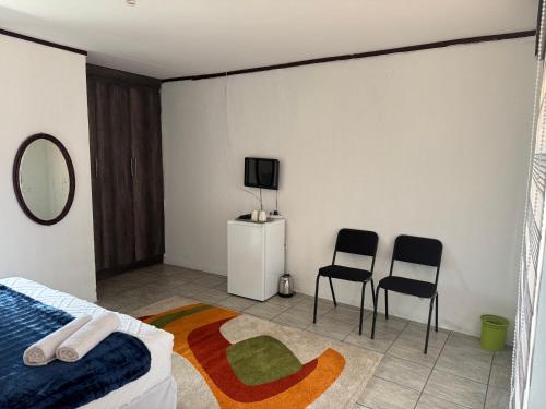 a bedroom with two chairs and a bed and a tv at Matrogwane BnB and Hall in Newcastle