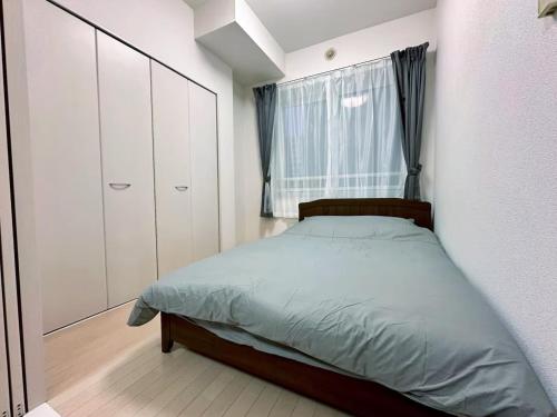 Un dormitorio con una cama y una ventana en 503好立地で札幌駅徒歩7分と大通駅徒歩6分で都心を満喫でき綺麗な部屋で快適が生活が実現, en Sapporo
