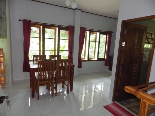 une salle à manger avec une table, des chaises et des fenêtres dans l'établissement Jasmin Resort, à Mae Hong Son