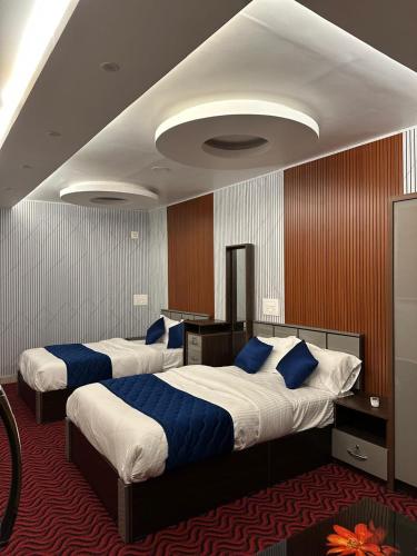 two beds in a hotel room with blue pillows at Thottunkal Tourist home in Kadavoor