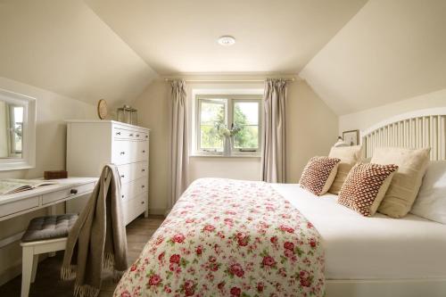 Schlafzimmer mit einem Bett, einer Kommode und Fenstern in der Unterkunft The Barn in South Cerney