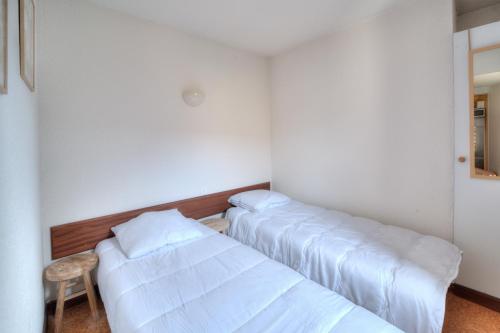 two beds in a room with white walls at Résidence La Chapelle - Cœur de station in Lélex