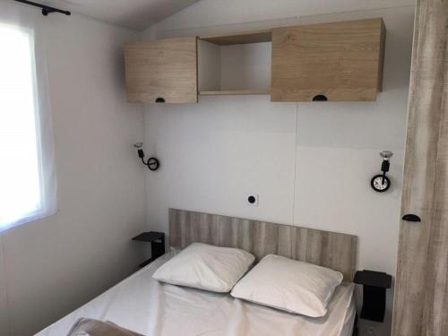 ein Bett mit zwei weißen Kissen in einem Zimmer in der Unterkunft Mobilhome Malaga Climatisé 32 in Saint-Martial-de-Nabirat