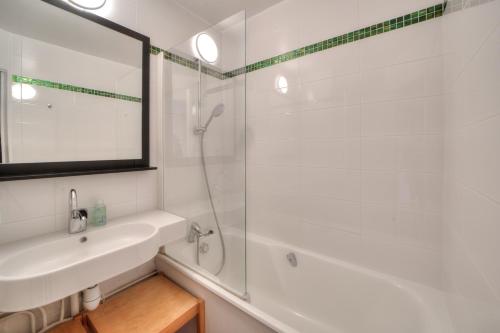 a white bathroom with a sink and a shower at Résidence La Chapelle - Cœur de station in Lélex