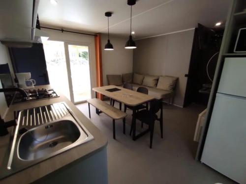 eine Küche mit Spüle, Tisch und Couch in der Unterkunft Mobilhome Agora climatisé 50 in Saint-Martial-de-Nabirat