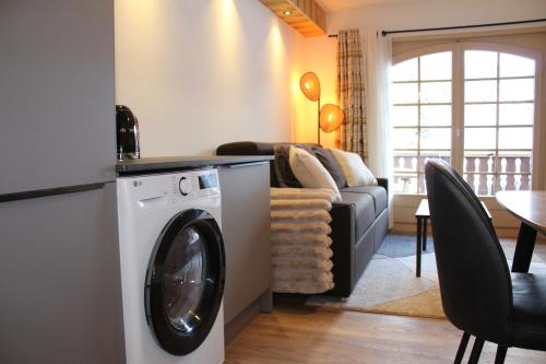 a living room with a washing machine and a couch at Centre, Pistes à pied, Vue magnifique, Calme, Tout renové, Grande terrasse in Les Gets
