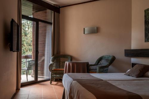 a bedroom with a bed and chairs and a window at Hotel Baztan in Garzáin