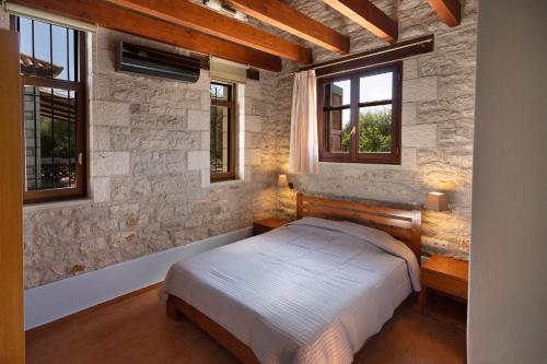 a bedroom with a bed in a stone wall at Asfendamos in Kakovatos