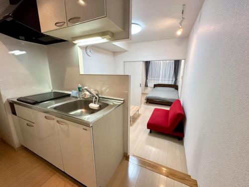 a small kitchen with a sink and a red chair at 503好立地で札幌駅徒歩7分と大通駅徒歩6分で都心を満喫でき綺麗な部屋で快適が生活が実現 in Sapporo