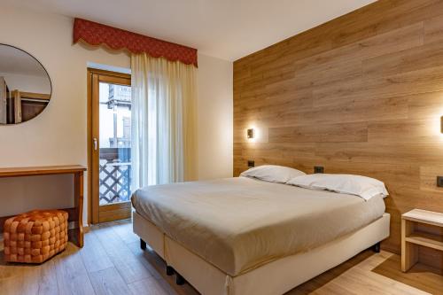 Un dormitorio con una cama grande y un espejo. en Hotel Italo, en Madonna di Campiglio
