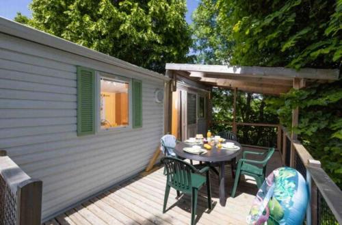 a wooden deck with a table and chairs on it at ZEcamping 4 étoiles familial - parc aqua et soirées animées in Murol