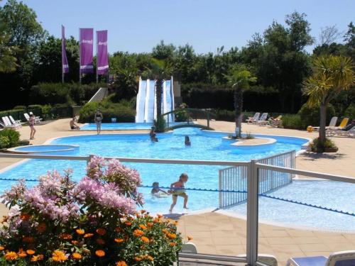 a group of people in a swimming pool with a waterfall at ZEcamping 4 étoiles familial avec étang de pêche et piscine chauffée in La Haye-du-Puits