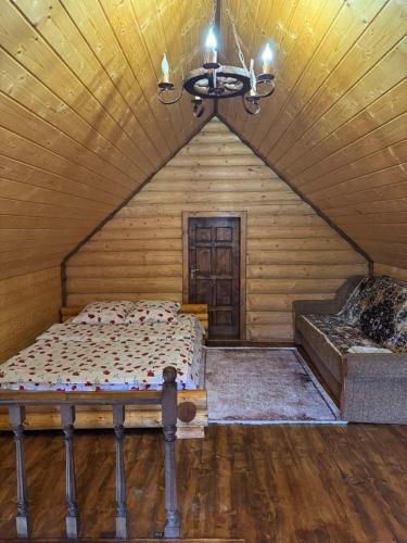 a bedroom with a bed and a chandelier at Лісовий котедж in Synevyrsʼka Polyana