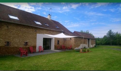 a brick house with red chairs in a yard at Au Gîte Savignéen in Savigné-lʼÉvêque