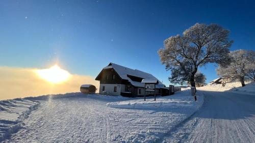a barn in the snow with the sun behind it at Aparthotel Teddy Kvilda in Kvilda