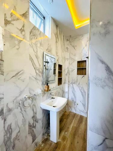 een witte badkamer met een wastafel en een spiegel bij VillAïda Appartement 001 in Darou Rhamane