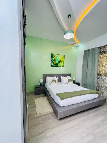 een slaapkamer met een groot bed en een groene muur bij VillAïda Appartement 001 in Darou Rhamane