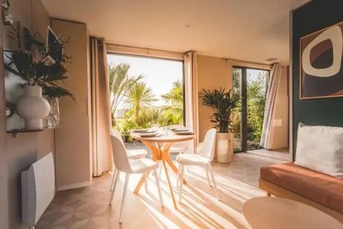 - un salon avec une table, des chaises et une grande fenêtre dans l'établissement Camping 4 étoiles - Piscine - eec0di, à Fouesnant
