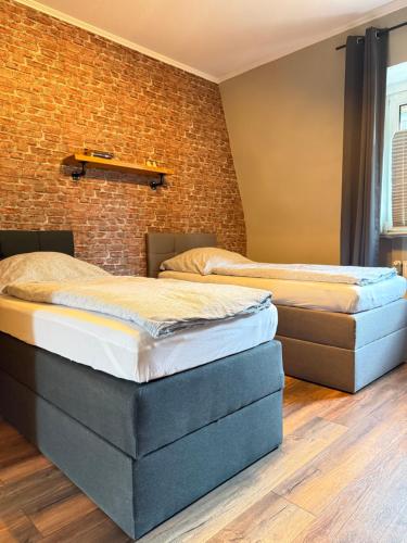 two beds in a room with a brick wall at Industrial Style 77qm mit Balkon in Herne