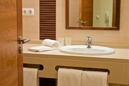 a bathroom with a sink and a mirror and towels at Silmar in Albufeira