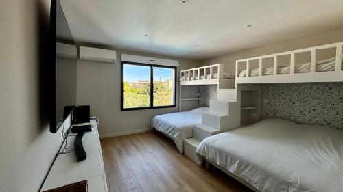 um quarto com duas camas, uma televisão e uma janela em Villa premium, tribu friendly, vaste patio & piscine em Mauguio