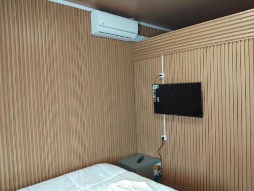 une chambre avec un lit et une télévision au mur dans l'établissement Residencial Bom Desc & Conforto, à Santo António