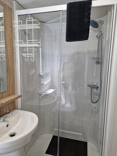 a white bathroom with a shower and a sink at Our Sea View - Heysham in Heysham