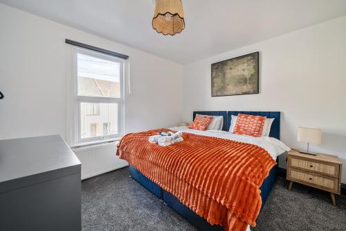 a bedroom with a bed with an orange blanket at Modern Bletchley home with stylish decor in Bletchley