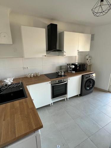 a kitchen with white cabinets and a stove top oven at Le Toit des Volcans - 8 couchages - Terrasse privée et Wifi in Clermont-Ferrand