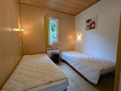 deux lits dans une petite pièce avec une fenêtre dans l'établissement VVF Sud Aveyron, à Brusque