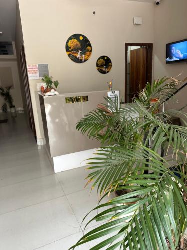 Un vestíbulo con una planta en maceta y platos en la pared. en Amaar hotel, en Rāmnagar