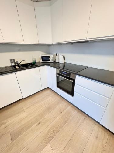 une cuisine avec des armoires blanches et un plancher en bois dans l'établissement Guesthouse good location, à Oslo