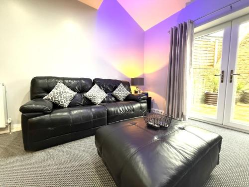 a living room with a black leather couch and a table at Maggie's Lodge in Leeds