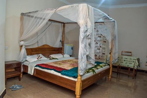una camera da letto con un letto a baldacchino in una stanza di Biez Homestay a Karatu