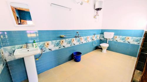 une salle de bain bleue avec un lavabo et des toilettes dans l'établissement Accomoon River Side Cottages, à Dirang Dzong