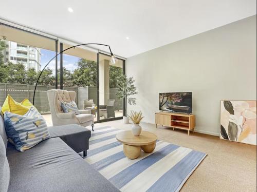a living room with a couch and a tv at Chatswood Gem Steps to Metro, Mall & Park in Sydney