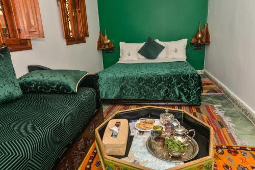una habitación verde con una cama y un sofá con una bandeja de comida en Riad ouhmidi, en Marrakech