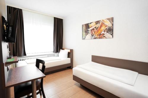 a hotel room with a bed and a table and a couch at Hotel Frohnhauser Hof in Essen